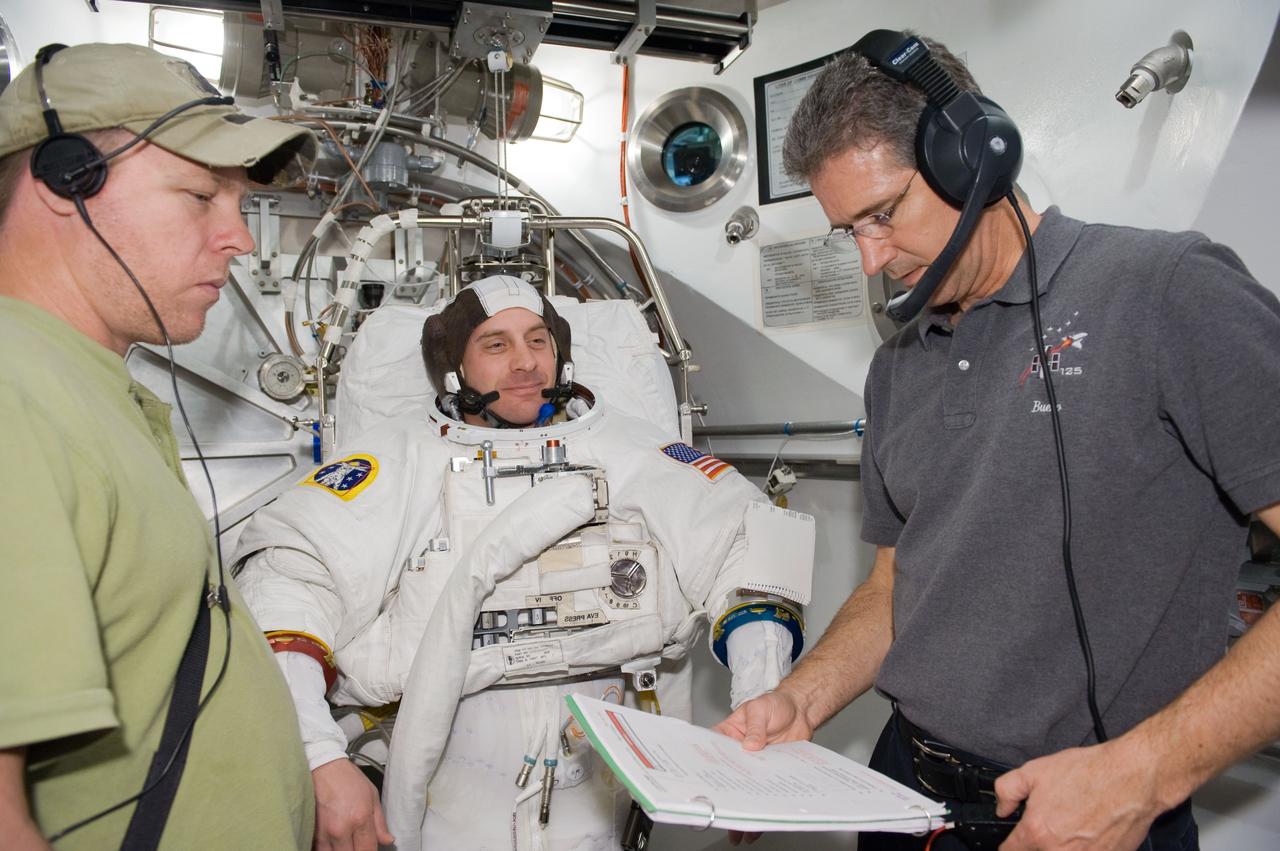 JSC2010-E-041258 (17 March 2010) --- NASA astronaut Garrett Reisman, STS-132 mission specialist, participates in an Extravehicular Mobility Unit (EMU) spacesuit fit check in the Space Station Airlock Test Article (SSATA) in the Crew Systems Laboratory at NASA's Johnson Space Center. Astronaut Michael Good (right), mission specialist, assisted Reisman.