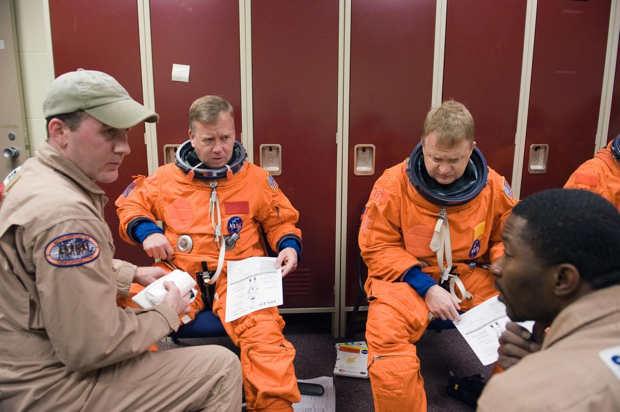 JSC2010-E-042076 (23 March 2010) --- NASA astronauts Steve Lindsey (left background), STS-133 commander; and Eric Boe (right background), pilot, attired in training versions of their shuttle launch and entry suits, prepare for a training session in the Space Vehicle Mock-up Facility at NASA's Johnson Space Center. United Space Alliance suit technicians assisted Lindsey and Boe.