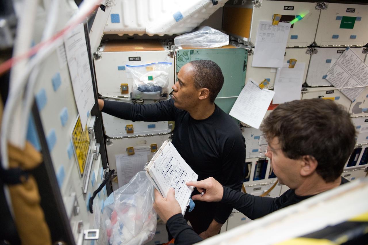 JSC2010-E-042099 (23 March 2010) --- NASA astronauts Michael Barratt (foreground) and Alvin Drew, both STS-133 mission specialists, participate in a post insertion/de-orbit training session on the middeck of the crew compartment trainer (CCT-2) in the Space Vehicle Mockup Facility at NASA's Johnson Space Center.