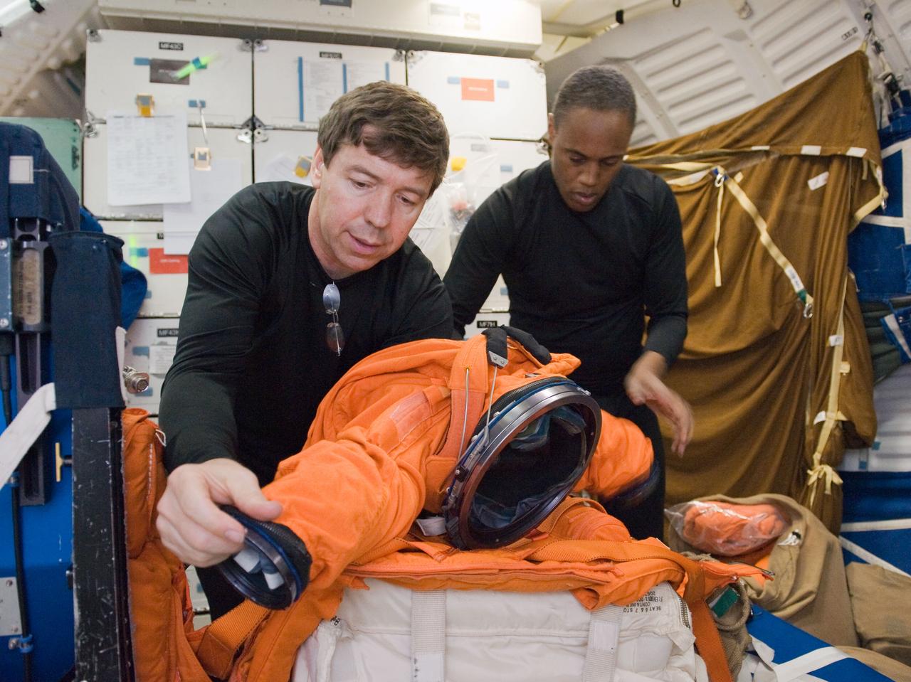 JSC2010-E-042104 (23 March 2010) --- NASA astronauts Michael Barratt (left) and Alvin Drew, both STS-133 mission specialists, participate in a post insertion/de-orbit training session on the middeck of the crew compartment trainer (CCT-2) in the Space Vehicle Mockup Facility at NASA's Johnson Space Center.