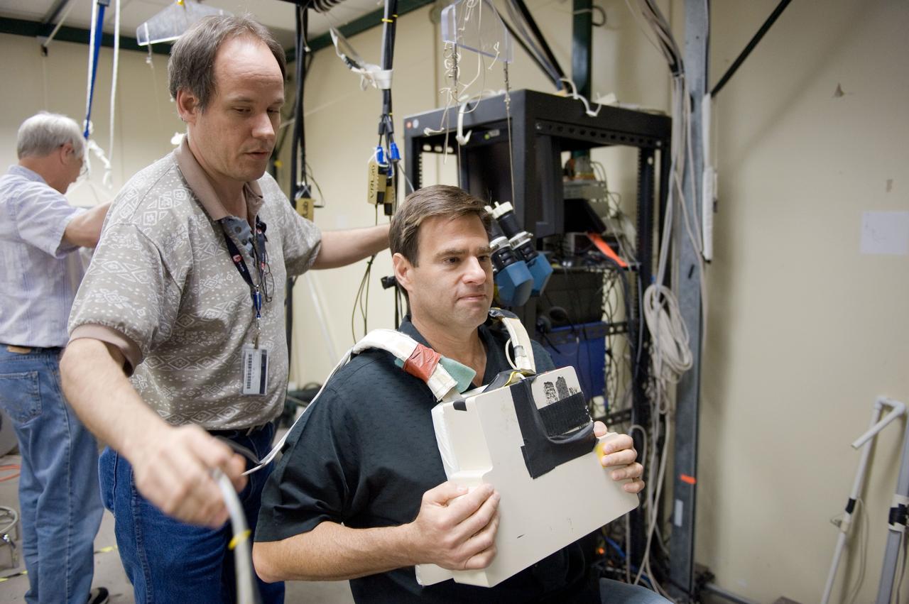 JSC2010-E-043658 (25 March 2010) --- NASA astronaut Greg Chamitoff, STS-134 mission specialist, prepares to use virtual reality hardware in the Space Vehicle Mock-up Facility at NASA's Johnson Space Center to rehearse some of his duties on the upcoming mission to the International Space Station. This type of virtual reality training allows the astronauts to wear a helmet and special gloves while looking at computer displays simulating actual movements around the various locations on the station hardware with which they will be working. Crew instructor Bradley Bell assisted Chamitoff.