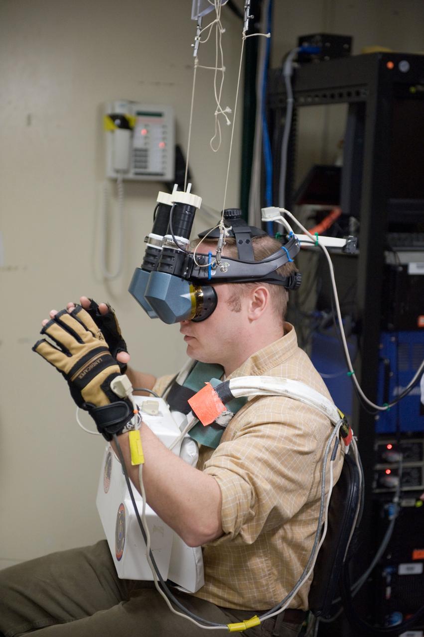 JSC2010-E-043659 (25 March 2010) --- NASA astronaut Michael Fincke, STS-134 mission specialist, uses virtual reality hardware in the Space Vehicle Mock-up Facility at NASA's Johnson Space Center to rehearse some of his duties on the upcoming mission to the International Space Station. This type of virtual reality training allows the astronauts to wear a helmet and special gloves while looking at computer displays simulating actual movements around the various locations on the station hardware with which they will be working.