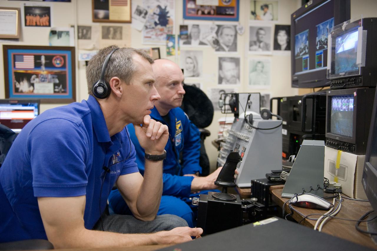 JSC2010-E-043668 (25 March 2010) --- NASA astronauts Mark Kelly (background), STS-134 commander; and Andrew Feustel, mission specialist, use the virtual reality lab in the Space Vehicle Mock-up Facility at NASA's Johnson Space Center to train for some of their duties aboard the space shuttle and space station. This type of computer interface, paired with virtual reality training hardware and software, helps to prepare crew members for dealing with space station elements.