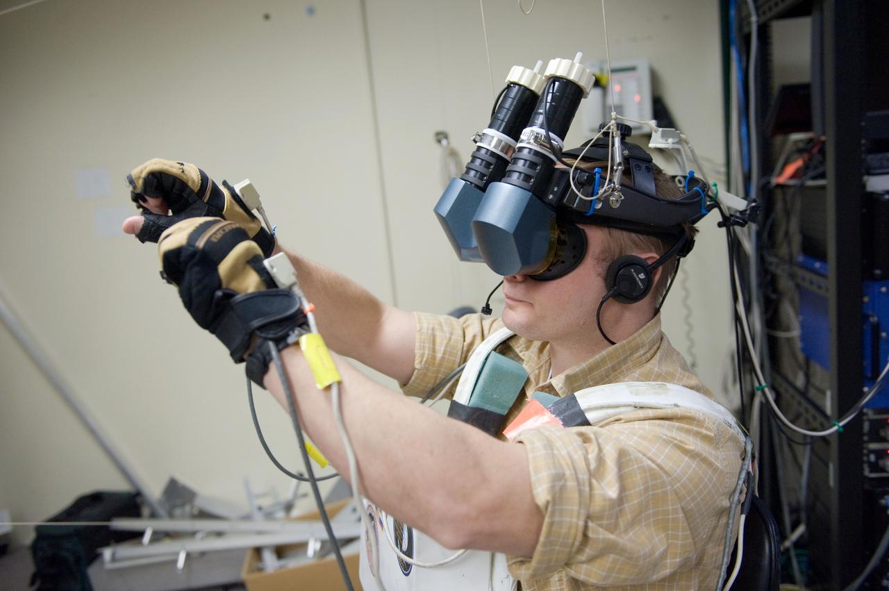JSC2010-E-043685 (25 March 2010) --- NASA astronaut Michael Fincke, STS-134 mission specialist, uses virtual reality hardware in the Space Vehicle Mock-up Facility at NASA's Johnson Space Center to rehearse some of his duties on the upcoming mission to the International Space Station. This type of virtual reality training allows the astronauts to wear a helmet and special gloves while looking at computer displays simulating actual movements around the various locations on the station hardware with which they will be working.