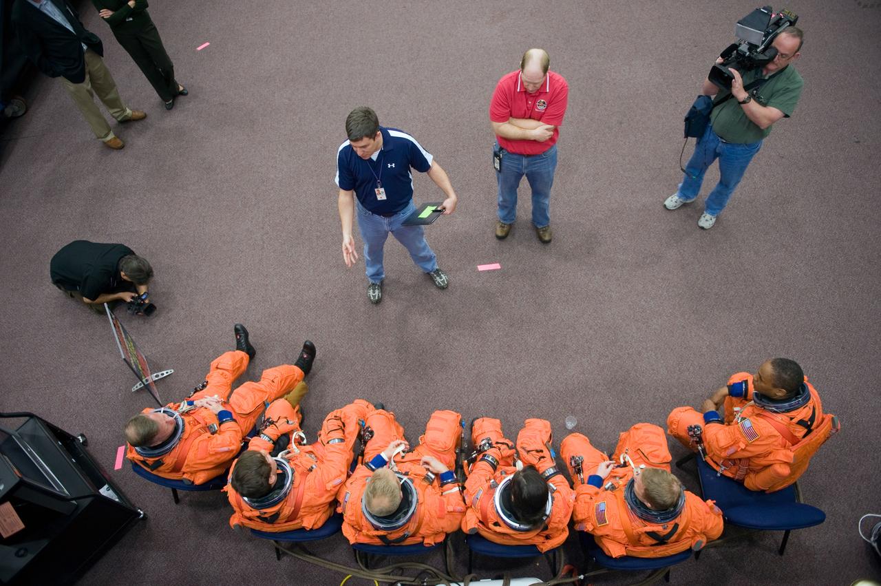 JSC2010-E-043956 (26 March 2010) --- Crew instructors brief the STS-133 crew members prior to the start of a training session in the crew compartment trainer (CCT-2) in the Space Vehicle Mockup Facility at NASA's Johnson Space Center. Pictured from the left (bottom) are NASA astronauts Steve Lindsey, commander; Michael Barratt, Tim Kopra, Nicole Stott, all mission specialists; Eric Boe, pilot; and Alvin Drew, mission specialist. The crew members are wearing training versions of their shuttle launch and entry suits.