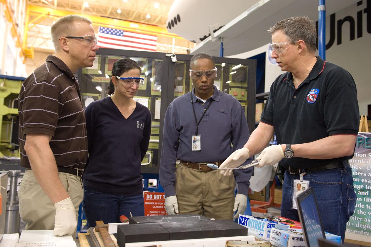 JSC2010-E-044333 (30 March 2010) --- NASA astronauts Tim Kopra (left), Nicole Stott and Alvin Drew, all STS-133 mission specialists, participate in an EVA tile repair training session in the Space Vehicle Mockup Facility at NASA's Johnson Space Center. Instructor John Ray (right) assisted the crew members.