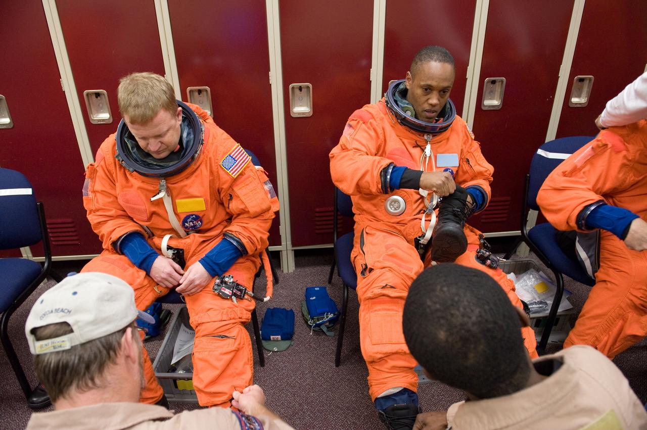 JSC2010-E-046376 (31 March 2010) --- NASA astronauts Eric Boe (left), STS-133 pilot; and Alvin Drew, mission specialists, don training versions of their shuttle launch and entry suits in preparation for a training session in the Space Vehicle Mockup Facility at NASA's Johnson Space Center. United Space Alliance suit technicians assisted Boe and Drew.