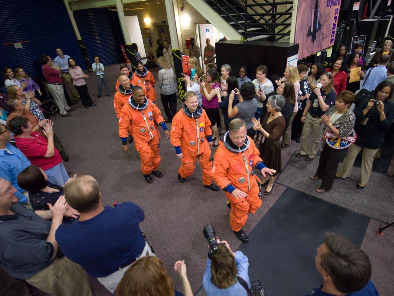 JSC2010-E-046380 (31 March 2010) --- Attired in training versions of their shuttle launch and entry suits, the STS-133 crew members are welcomed by a crowd as they enter the Space Vehicle Mockup Facility at NASA's Johnson Space Center for a training session. Pictured (front to back) are NASA astronauts Steve Lindsey, commander; Eric Boe, pilot; Alvin Drew, Tim Kopra, Michael Barratt and Nicole Stott, all mission specialists.