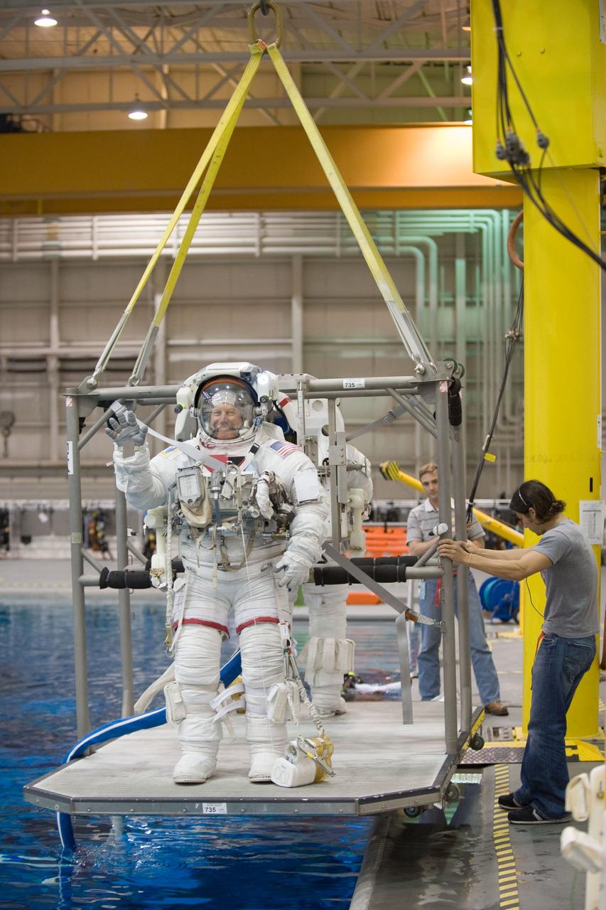 JSC2010-E-046459 (31 March 2010) --- NASA astronauts Tim Kopra and Alvin Drew (partially obscured), both STS-133 mission specialists, attired in training versions of their Extravehicular Mobility Unit (EMU) spacesuits, are about to be submerged in the waters of the Neutral Buoyancy Laboratory (NBL) near NASA's Johnson Space Center. Divers (out of frame) are in the water to assist the crew members in their rehearsal, intended to help prepare them for work on the exterior of the International Space Station.