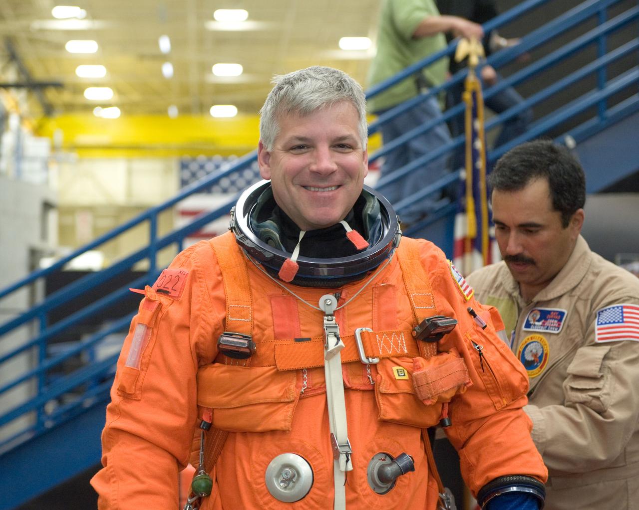 JSC2010-E-051957 (12 April 2010) --- NASA astronaut Gregory H. Johnson, STS-134 pilot, dons a training version of his shuttle launch and entry suit in preparation for a post insertion/de-orbit training session in the Space Vehicle Mock-up Facility at NASA's Johnson Space Center. United Space Alliance suit technician Raymond Cuevas assisted Johnson.