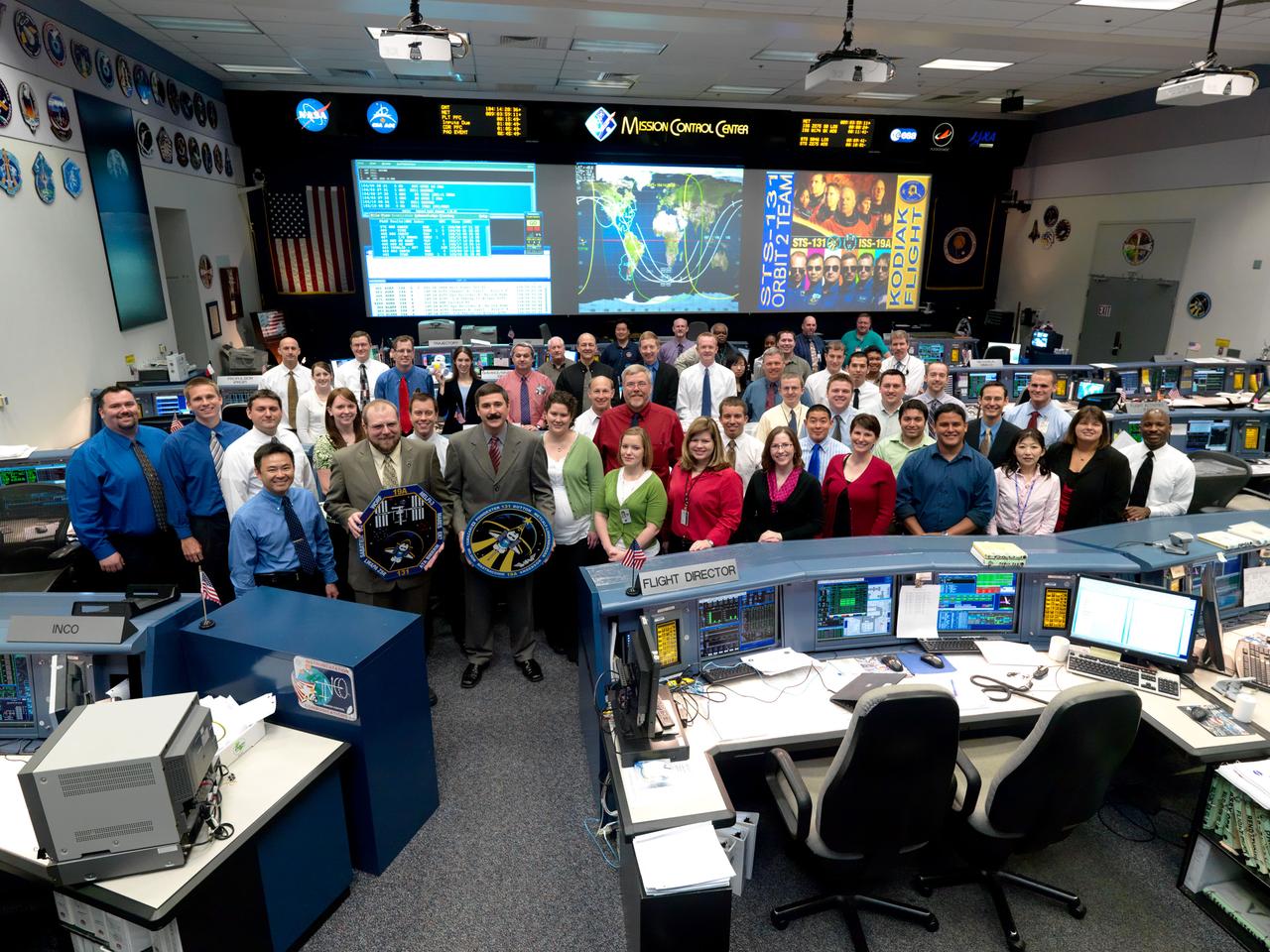 JSC2010-E-051978 (14 April 2010) --- The members of the STS-131 Orbit 2 flight control team pose for a group portrait in the space shuttle flight control room in the Mission Control Center at NASA's Johnson Space Center. Flight director Mike Sarafin holds the STS-131 mission logo.