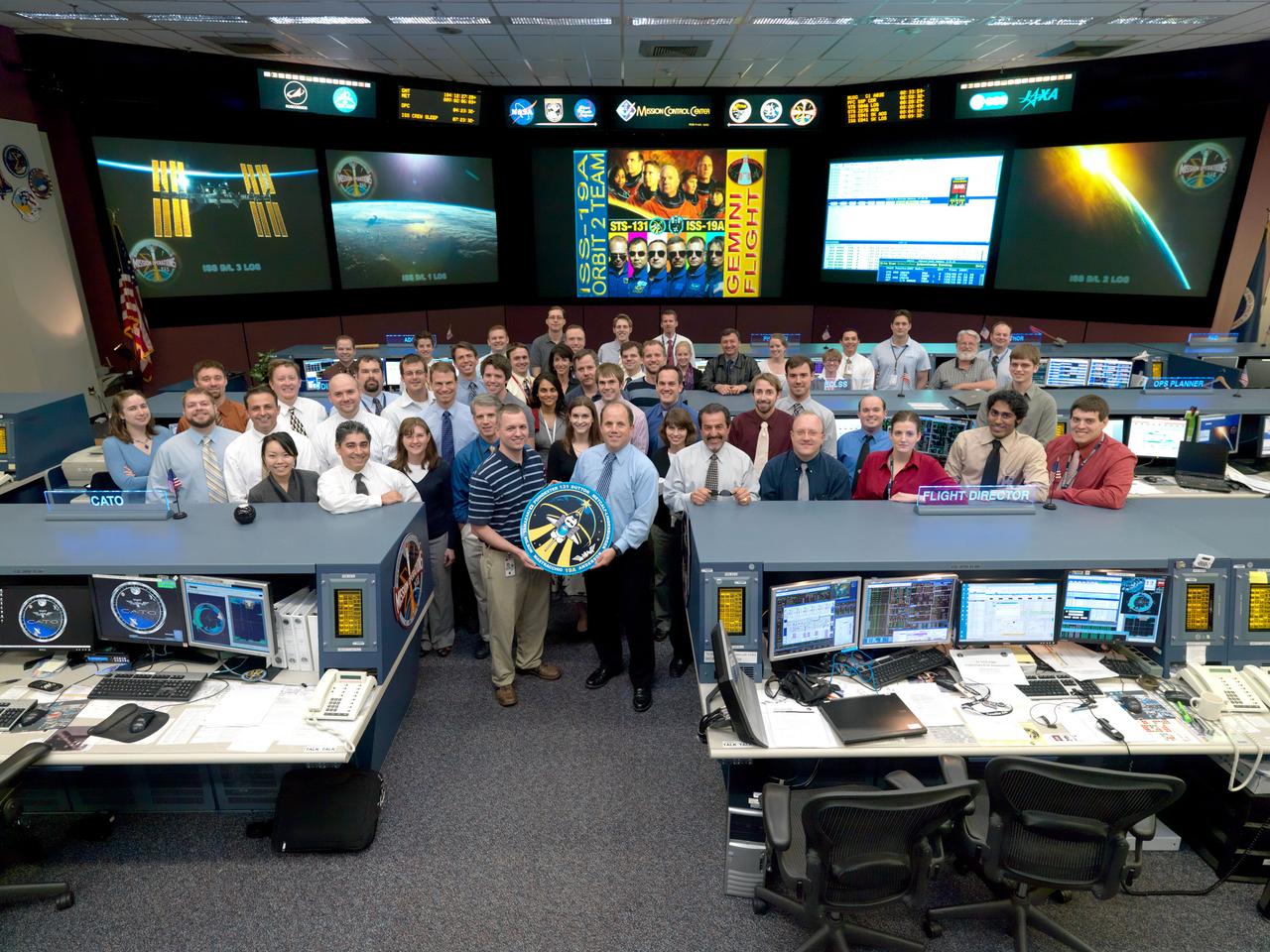 JSC2010-E-052008 (14 April 2010) --- The members of the STS-131/19A ISS Orbit 2 flight control team pose for a group portrait in the space station flight control room in the Mission Control Center at NASA's Johnson Space Center. Flight director Ron Spencer (right) holds the STS-131 mission logo.
