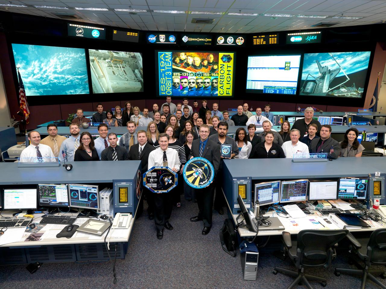 JSC2010-E-052556 (14 April 2010) --- The members of the STS-131/19A ISS Orbit 3 flight control team pose for a group portrait in the space station flight control room in the Mission Control Center at NASA's Johnson Space Center. Flight director Ed Van Cise holds the STS-131 mission logo.