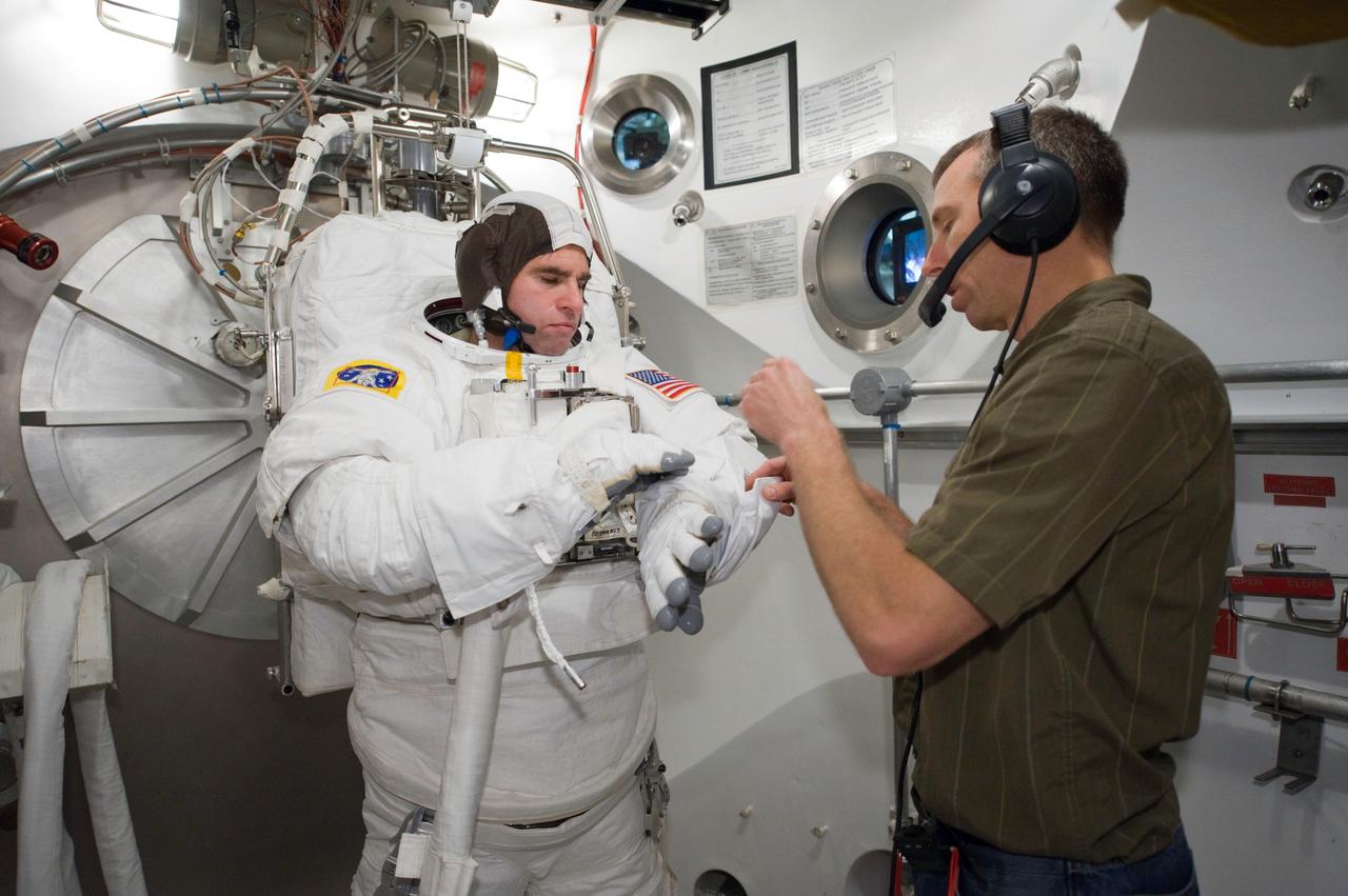 JSC2010-E-060727 (29 April 2010) --- NASA astronaut Greg Chamitoff, STS-134 mission specialist, participates in an Extravehicular Mobility Unit (EMU) spacesuit fit check in the Space Station Airlock Test Article (SSATA) in the Crew Systems Laboratory at NASA's Johnson Space Center. NASA astronaut Andrew Feustel, mission specialist, assisted Chamitoff.