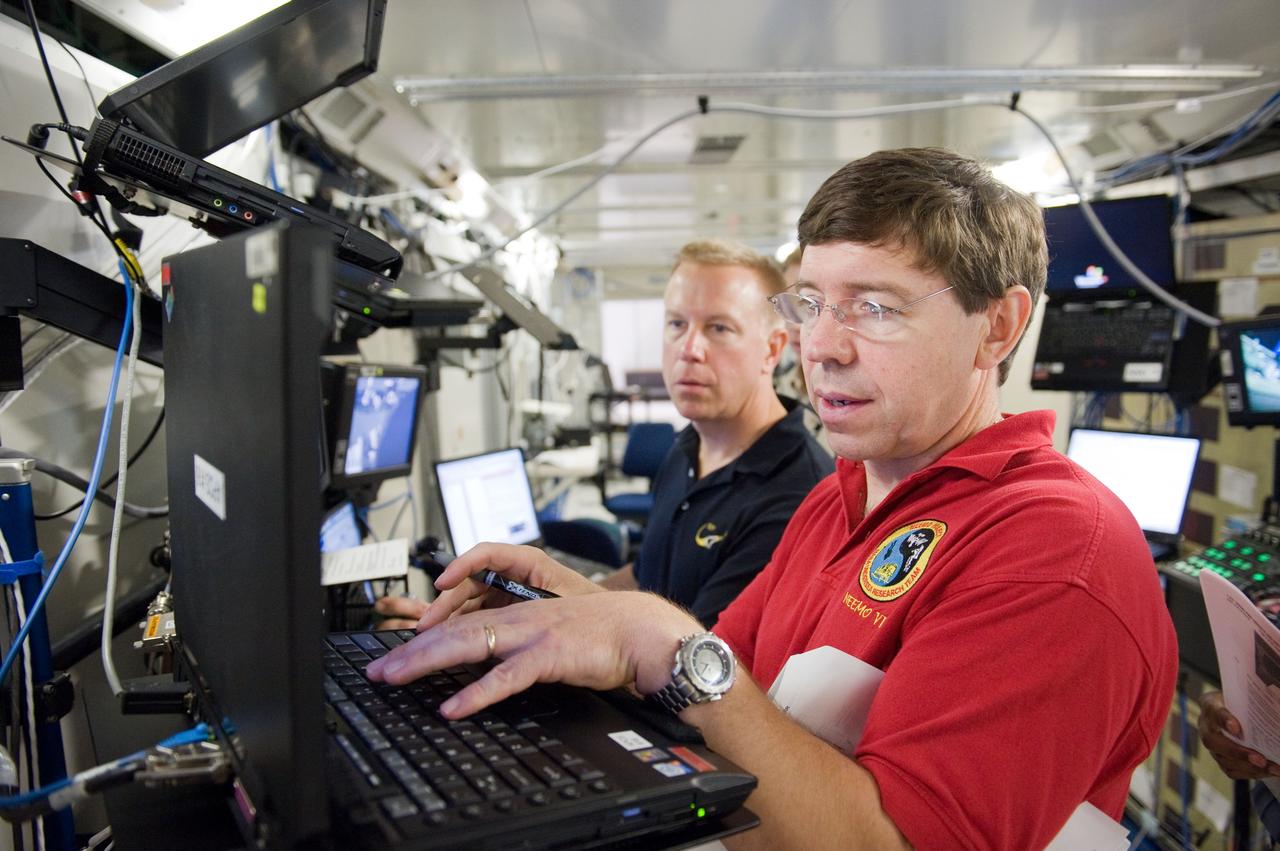 JSC2010-E-084019 (18 May 2010) --- NASA astronauts Michael Barratt (foreground) and Tim Kopra, both STS-133 mission specialists, participate in a robotics training session in the Jake Garn Simulation and Training Facility at NASA's Johnson Space Center.