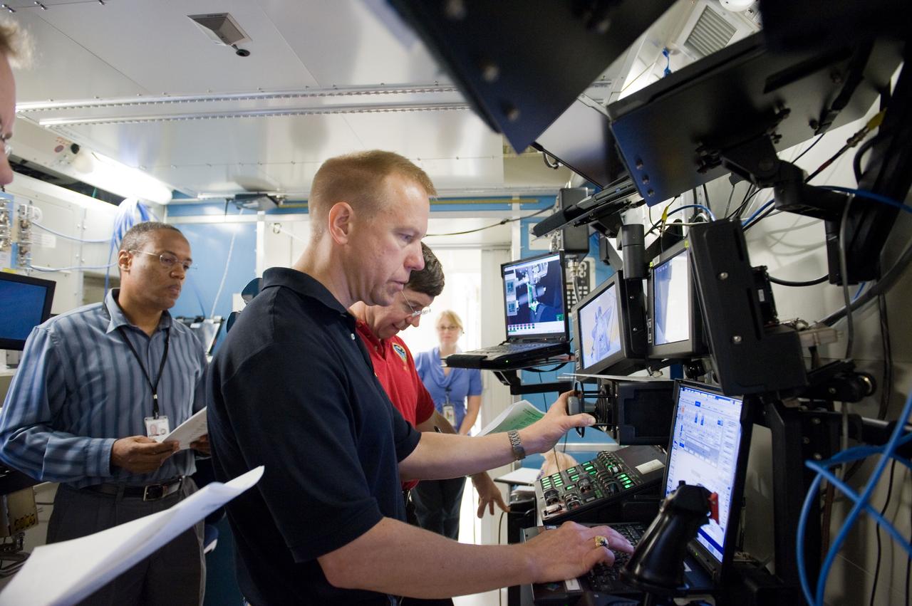 JSC2010-E-084020 (18 May 2010) --- NASA astronauts Tim Kopra (foreground), Michael Barratt (partially obscured) and Alvin Drew, all STS-133 mission specialists, participate in a robotics training session in the Jake Garn Simulation and Training Facility at NASA's Johnson Space Center.
