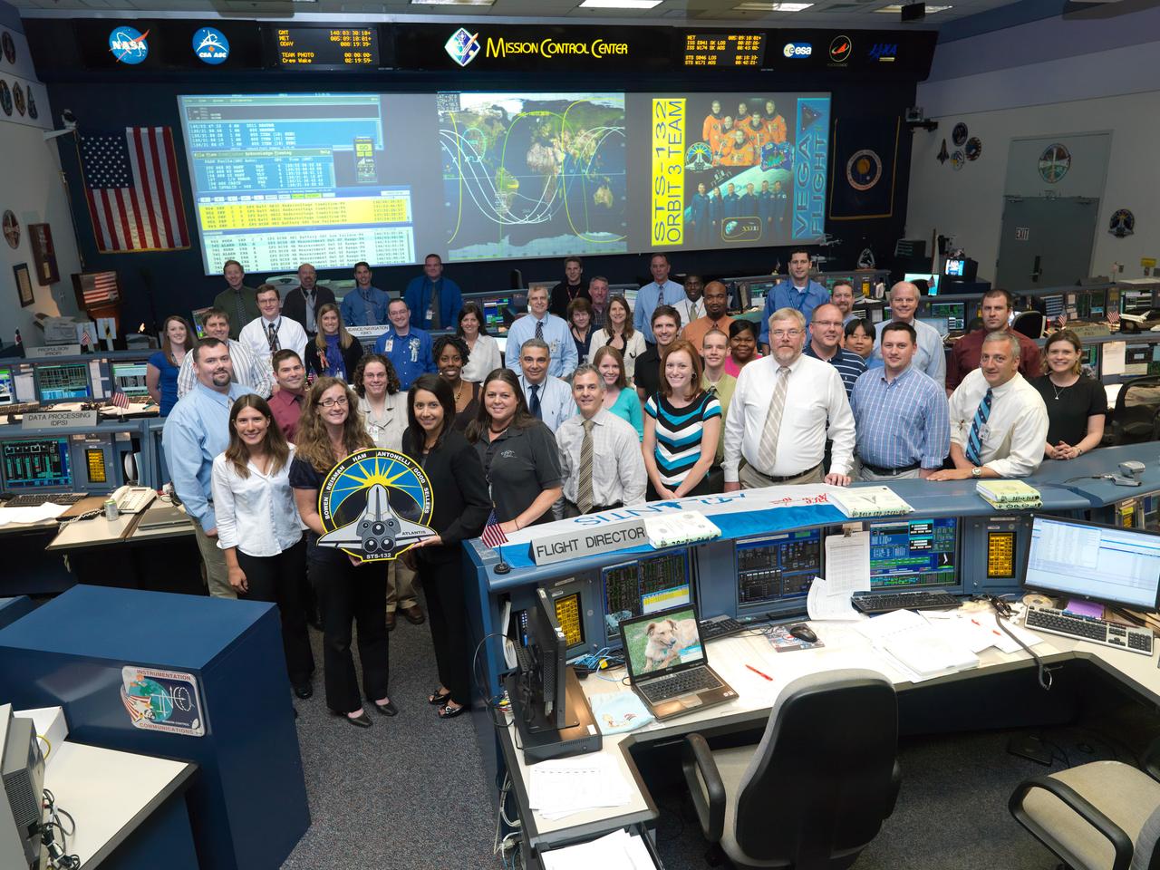JSC2010-E-085363 (19 May 2010) --- The members of the STS-132 Orbit 3 flight control team pose for a group portrait in the space shuttle flight control room in the Mission Control Center at NASA's Johnson Space Center. Flight director Ginger Kerrick (right) holds the STS-132 mission logo. Photo credit: NASA or National Aeronautics and Space Administration