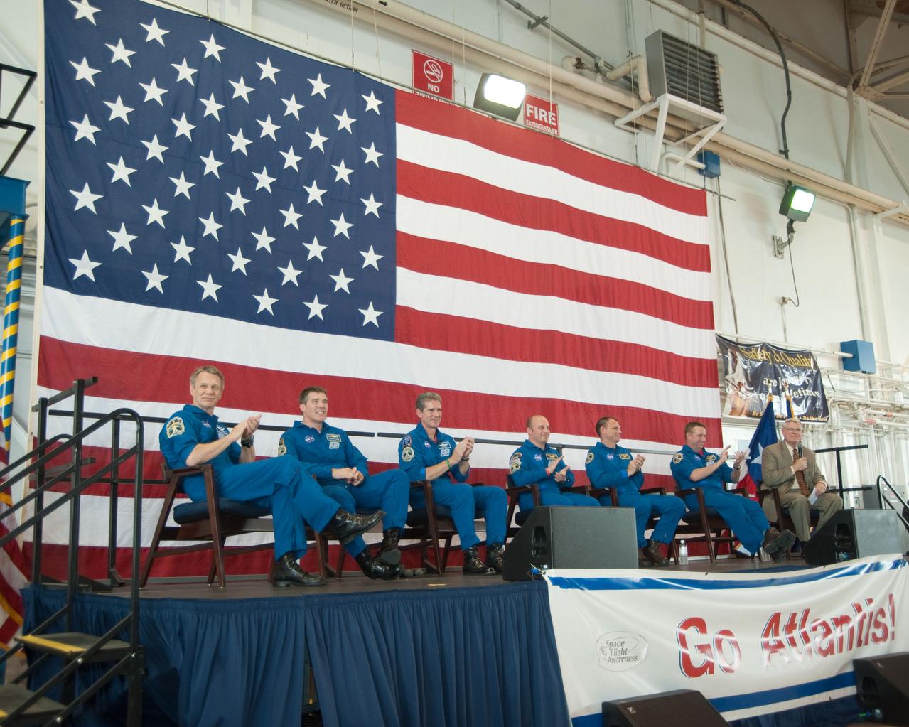 JSC2010-E-089697 (27 May 2010) ---  At Ellington Field's Hangar 276,   NASA's Johnson Space Center (JSC) director Michael L. Coats  (far right on stage), addresses a large crowd of visitors at the crew return ceremony for STS-132 -- space shuttle Atlantis' final scheduled mission.  Crew members, from the left, are NASA astronauts Piers Sellers, Steve Bowen, Michael Good, Garrett Reisman, Tony Antonelli and Ken Ham. Photo credit: NASA or National Aeronautics and Space Administration
