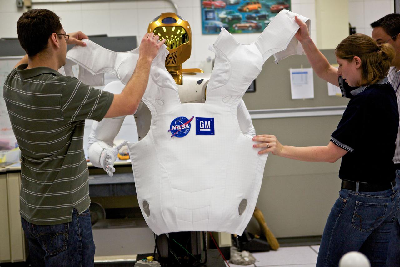 JSC2010-E-090928 (1 June 2010) --- Engineer Court Edmondson and soft goods designer Heather Bibby help Robonaut 2 try on its new flight suit. The materials in R2?s ?skin? were upgraded in preparation for the robot?s journey to the International Space Station due to the station?s stringent flammability requirements. R2 is scheduled to launch on board space shuttle Discovery as part of the STS-133 mission. Photo credit: NASA or National Aeronautics and Space Administration