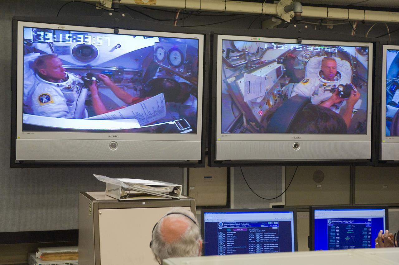 JSC2010-E-098603 (22 June 2010) --- NASA astronaut Tim Kopra, STS-133 mission specialist, is visible on the screens in the Space Station Airlock Test Article (SSATA) Control Room in the Crew Systems Laboratory at NASA?s Johnson Space Center during an Extravehicular Mobility Unit (EMU) spacesuit fit check.