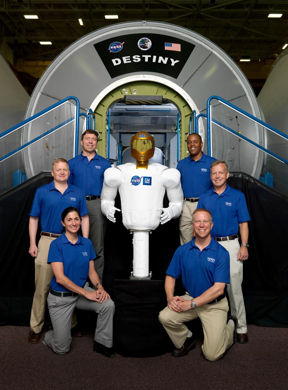 JSC2010-E-106911 (28 June 2010) --- NASA's Robonaut 2, or R2 for short, who will hitch a ride with the STS-133 crew members to travel to the International Space Station for a tour of duty beginning this fall, ?poses? near a Destiny lab trainer with the crew during a break in training. Clockwise from lower right, R2 is flanked by NASA astronauts Tim Kopra and Nicole Stott, both mission specialists; Eric Boe, pilot; Michael Barratt and Alvin Drew, both mission specialists, and Steve Lindsey, commander. Photo credit: NASA or National Aeronautics and Space Administration