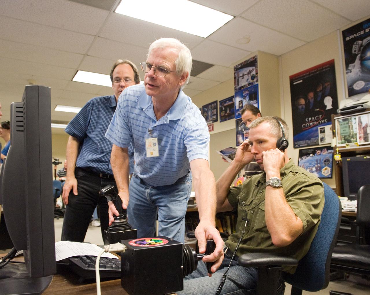 JSC2010-E-121045 (27 Aug. 2010) --- NASA astronaut Andrew Feustel (right), STS-134 mission specialist, uses the virtual reality lab in the Space Vehicle Mock-up Facility at NASA's Johnson Space Center to train for some of his duties aboard the space shuttle and space station. This type of computer interface, paired with virtual reality training hardware and software, helps to prepare crew members for dealing with space station elements. David Homan assisted Feustel. Photo credit: NASA or National Aeronautics and Space Administration