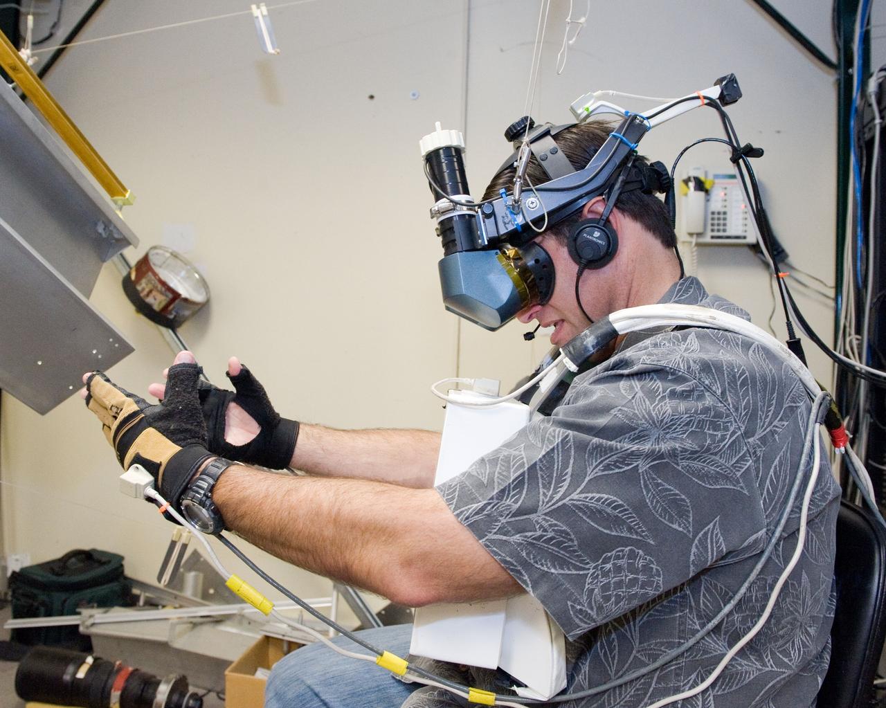 JSC2010-E-121053 (27 Aug. 2010) --- NASA astronaut Greg Chamitoff, STS-134 mission specialist, uses virtual reality hardware in the Space Vehicle Mock-up Facility at NASA's Johnson Space Center to rehearse some of his duties on the upcoming mission to the International Space Station. This type of virtual reality training allows the astronauts to wear a helmet and special gloves while looking at computer displays simulating actual movements around the various locations on the station hardware with which they will be working. Photo credit: NASA or National Aeronautics and Space Administration