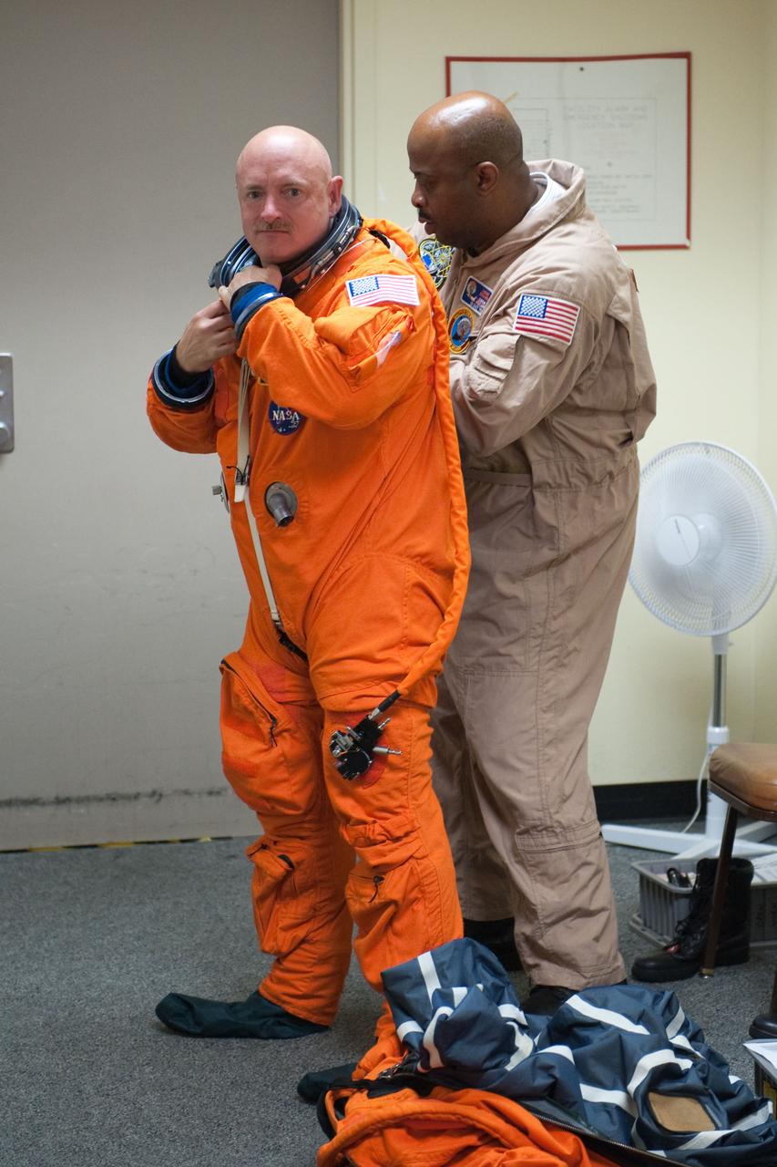JSC2010-E-124259 (8 Sept. 2010) --- NASA astronaut Mark Kelly, STS-134 commander, dons a training version of his shuttle launch and entry suit in preparation for a training session in the fixed-base shuttle mission simulator (SMS) in the Jake Garn Simulation and Training Facility at NASA?s Johnson Space Center. United Space Alliance suit technician Andre Denard assisted Kelly. Photo credit: NASA or National Aeronautics and Space Administration