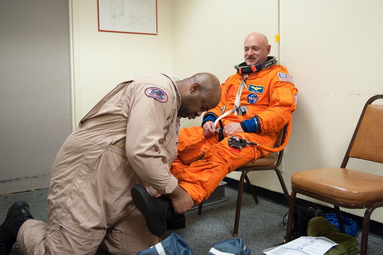 JSC2010-E-124261 (8 Sept. 2010) --- NASA astronaut Mark Kelly, STS-134 commander, dons a training version of his shuttle launch and entry suit in preparation for a training session in the fixed-base shuttle mission simulator (SMS) in the Jake Garn Simulation and Training Facility at NASA?s Johnson Space Center. United Space Alliance suit technician Andre Denard assisted Kelly. Photo credit: NASA or National Aeronautics and Space Administration