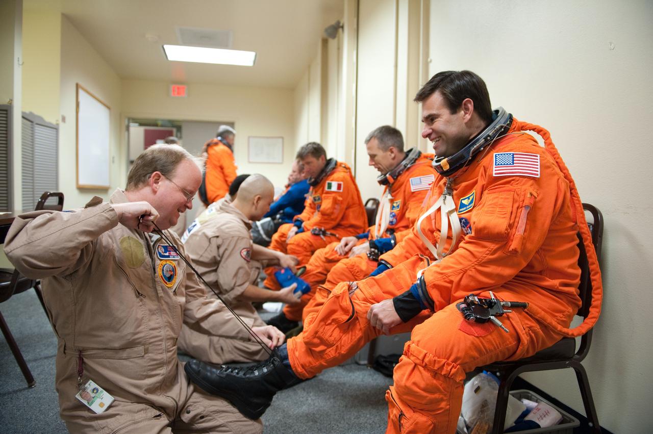 JSC2010-E-124264 (8 Sept. 2010) --- NASA astronauts Greg Chamitoff (foreground), Andrew Feustel and European Space Agency astronaut Roberto Vittori, all STS-134 mission specialists, don training versions of their shuttle launch and entry suits in preparation for a training session in the fixed-base shuttle mission simulator (SMS) in the Jake Garn Simulation and Training Facility at NASA?s Johnson Space Center. United Space Alliance suit technicians assisted the crew members. Photo credit: NASA or National Aeronautics and Space Administration