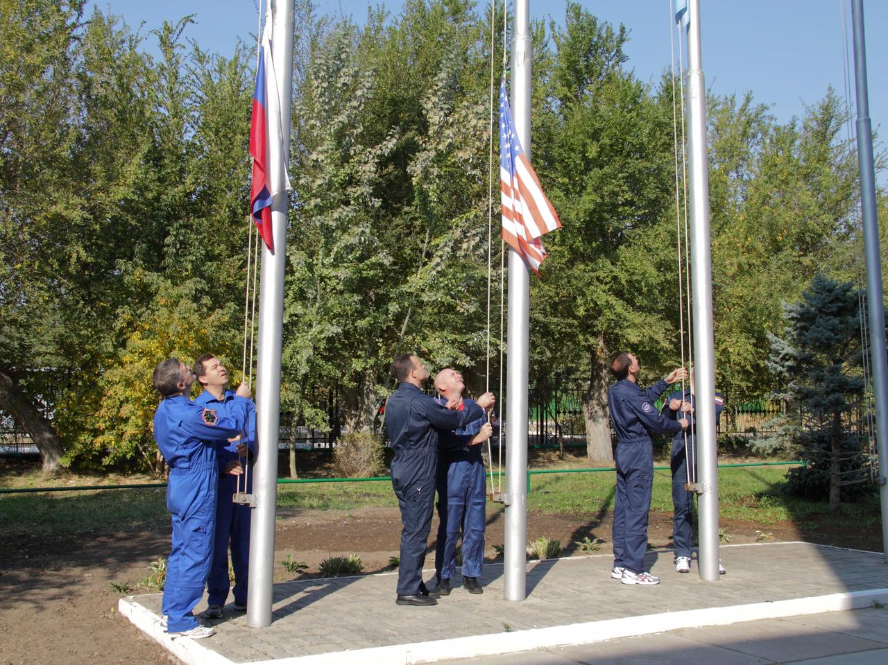 At the Baikonur Cosmodrome in Kazakhstan, the prime and backup crews of Expedition 25 conduct the traditional raising of flags outside their Cosmonaut Hotel crew quarters September 27, 2010. From left to right are prime crew Flight Engineers Alexander Kaleri and Oleg Skripochka raising the Russian flag, backup Ron Garan joining prime crewmember Scott Kelly to raise the American flag and backup crewmembers Sergei Volkov and Oleg Kononenko (hidden) raising the Kazakh flag.  Credit: NASA/Victor Zelentsov 