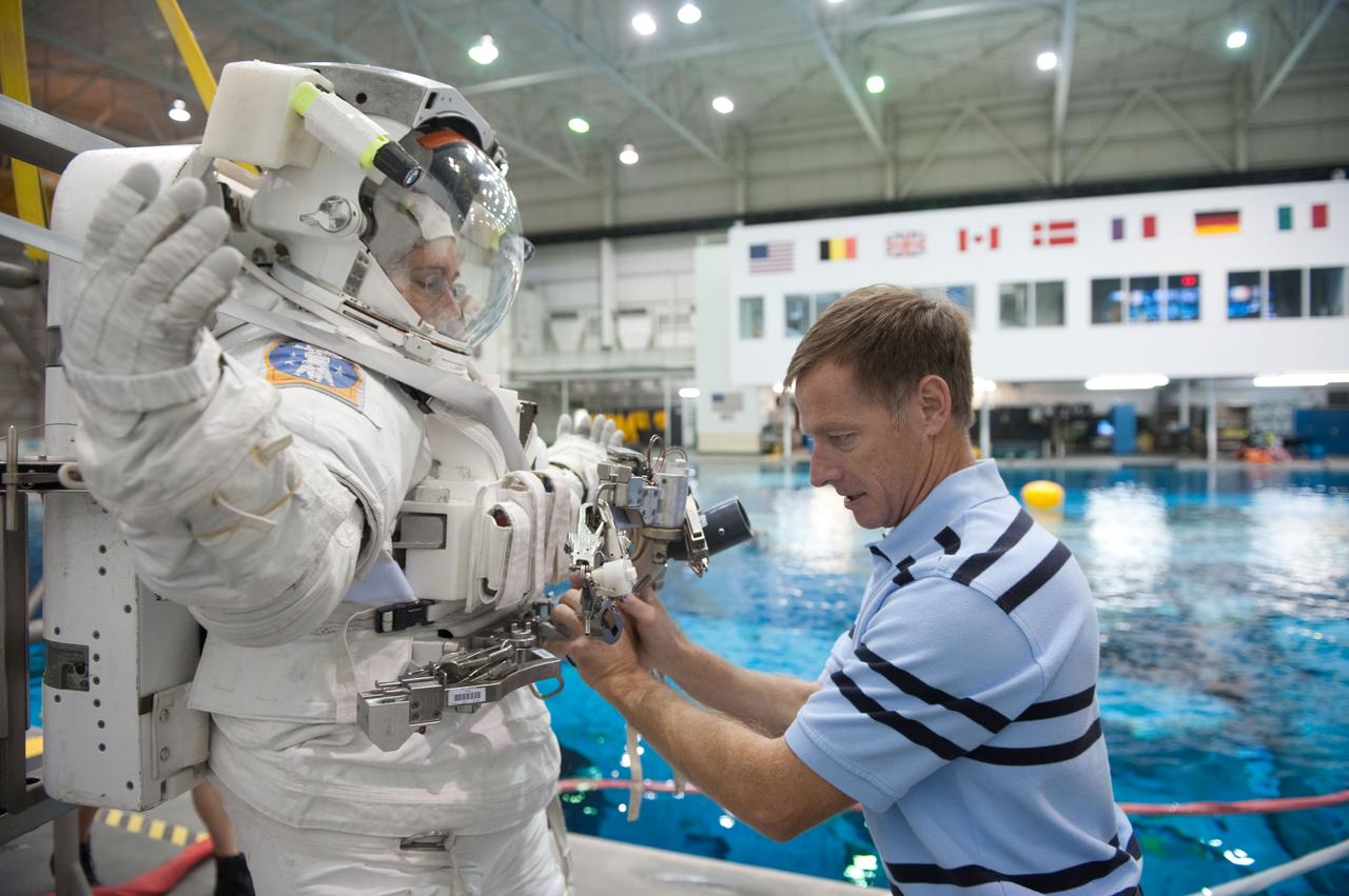 JSC2010-E-181466 (27 Oct. 2010) --- NASA astronaut Chris Ferguson, STS-135 commander, helps NASA astronaut Sandy Magnus, mission specialist, don a training version of her Extravehicular Mobility Unit (EMU) spacesuit in preparation for a spacewalk training session in the waters of the Neutral Buoyancy Laboratory (NBL) near NASA's Johnson Space Center. STS-135 is planned to be the final mission of the space shuttle program. Photo credit: NASA or National Aeronautics and Space Administration