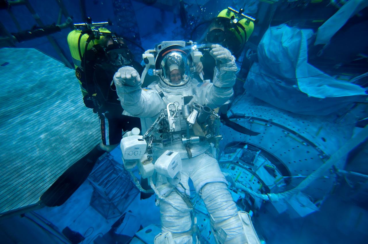 JSC2010-E-181484 (27 Oct. 2010) --- Attired in a training version of her Extravehicular Mobility Unit (EMU) spacesuit, NASA astronaut Sandy Magnus, STS-135 mission specialist, participates in a spacewalk training session in the waters of the Neutral Buoyancy Laboratory (NBL) near NASA's Johnson Space Center. Divers are in the water to assist Magnus in her rehearsal, which is intended to help prepare her for work on the exterior of the International Space Station. STS-135 is planned to be the final mission of the space shuttle program. Photo credit: NASA or National Aeronautics and Space Administration