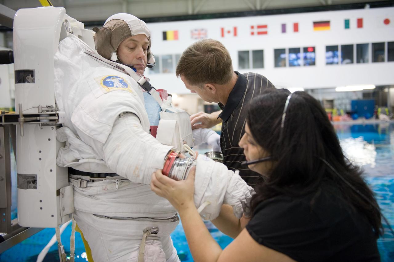 JSC2010-E-187211 (22 Nov. 2010) --- NASA astronaut Ron Garan, Expedition 27/28 flight engineer, gets help donning a training version of his Extravehicular Mobility Unit (EMU) spacesuit in preparation for a spacewalk training session in the waters of the Neutral Buoyancy Laboratory (NBL) near NASA's Johnson Space Center. NASA astronaut Chris Ferguson, STS-135 commander, and a suit technician assisted Garan. Photo credit: NASA or National Aeronautics and Space Administration
