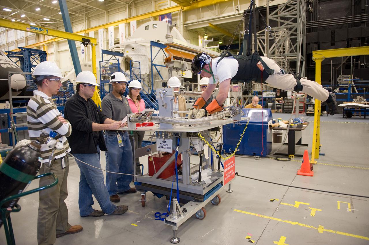 JSC2010-E-193887 (1 Dec. 2010) --- NASA astronaut Michael Fincke, STS-134 mission specialist, participates in an extravehicular activity (EVA) training session in the Partial Gravity Simulator (POGO) test area in the Space Vehicle Mock-up Facility at NASA?s Johnson Space Center. NASA astronauts Andrew Feustel (left) and Greg Chamitoff (second left), both mission specialists, look on. Photo credit: NASA or National Aeronautics and Space Administration