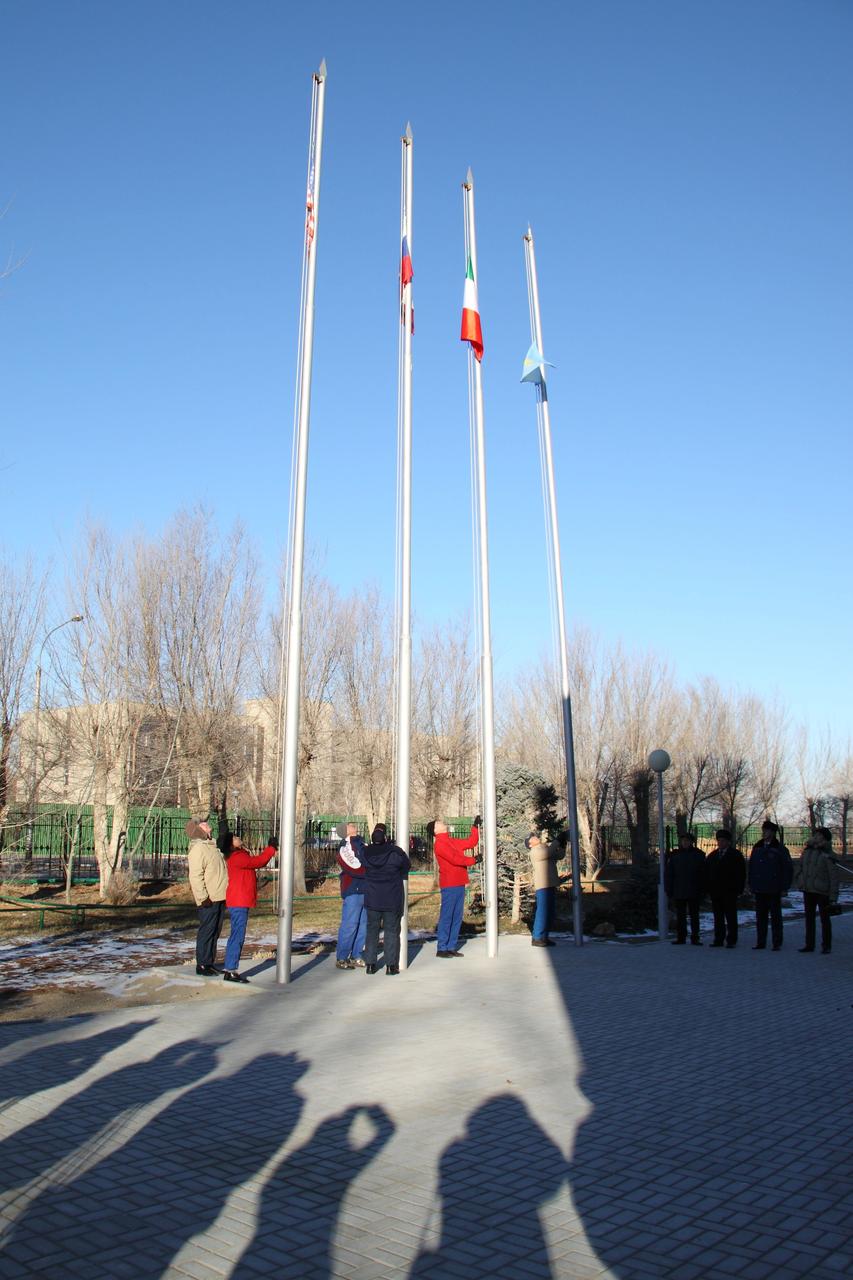The flags of the United States, Russia, Italy and Kazakhstan are raised outside the Cosmonaut Hotel crew quarters in Baikonur, Kazakhstan December 5, 2010 in the traditional ceremony for the Expedition 26 prime and backup crewmembers that is part of their prelaunch activities. NASA Flight Engineer Catherine Coleman, Soyuz Commander Dmitry Kondratyev and European Space Agency Flight Engineer Paolo Nespoli of Italy are scheduled to launch December 16 (Baikonur time) in their Soyuz TMA-20 spacecraft to the International Space Station.  Credit: NASA/Victor Zelentsov 