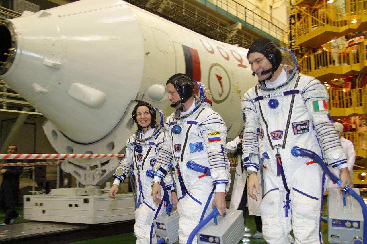At the Baikonur Cosmodrome in Kazakhstan, Expedition 26 Flight Engineer Catherine Coleman of NASA (left), Soyuz Commander Dmitry Kondratyev (center) and Flight Engineer Paolo Nespoli of the European Space Agency (right) walk past their Soyuz booster December 4, 2010 during a fit check of their Soyuz TMA-20 spacecraft. The trio will launch December 16 (Baikonur time) to the International Space Station.  Credit: NASA/Victor Zelentsov 