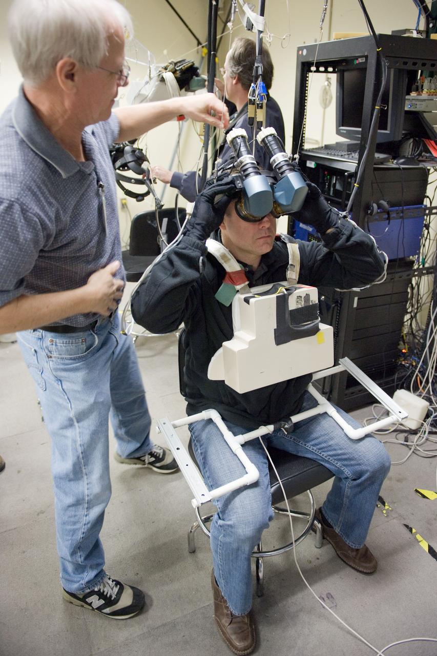JSC2011-E-003209 (18 Jan. 2011) --- NASA astronaut Ron Garan, Expedition 27/28 flight engineer, uses virtual reality hardware in the Space Vehicle Mock-up Facility at NASA's Johnson Space Center to rehearse some of his duties on the upcoming mission to the International Space Station. This type of virtual reality training allows the astronauts to wear a helmet and special gloves while looking at computer displays simulating actual movements around the various locations on the station hardware with which they will be working. David Homan assisted Garan. Photo credit: NASA or National Aeronautics and Space Administration