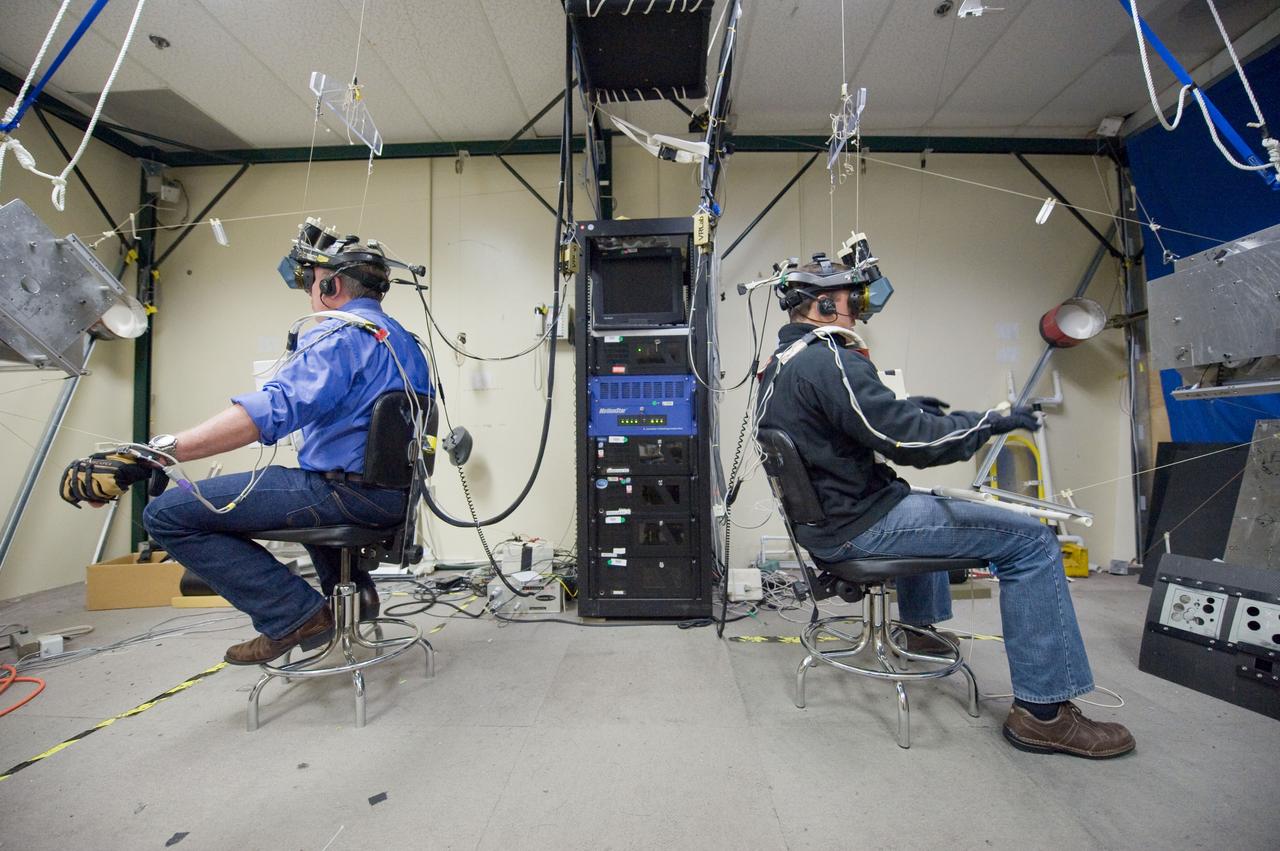 JSC2011-E-003213 (18 Jan. 2011) --- NASA astronauts Mike Fossum (left), Expedition 28 flight engineer and Expedition 29 commander; and Ron Garan, Expedition 27/28 flight engineer,  use virtual reality hardware in the Space Vehicle Mock-up Facility at NASA's Johnson Space Center to rehearse some of his duties on the upcoming mission to the International Space Station. This type of virtual reality training allows the astronauts to wear a helmet and special gloves while looking at computer displays simulating actual movements around the various locations on the station hardware with which they will be working. Photo credit: NASA or National Aeronautics and Space Administration