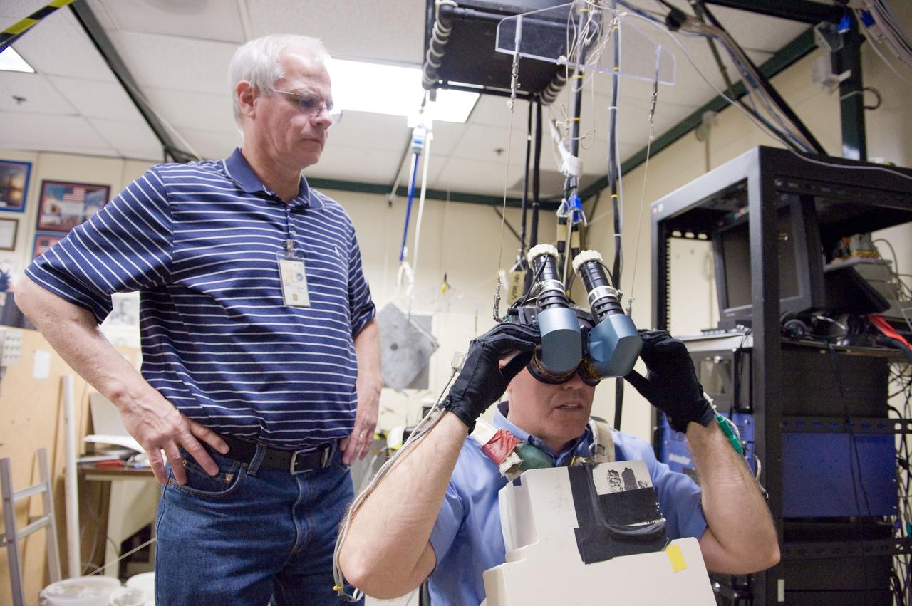 JSC2011-E-006295 (24 Jan. 2011) --- NASA astronaut Steve Bowen, STS-133 mission specialist, uses virtual reality hardware in the Space Vehicle Mock-up Facility at NASA's Johnson Space Center to rehearse some of his duties on the upcoming mission to the International Space Station. This type of virtual reality training allows the astronauts to wear a helmet and special gloves while looking at computer displays simulating actual movements around the various locations on the station hardware with which they will be working. Crew trainer David Homan assisted Bowen. Photo credit: NASA or National Aeronautics and Space Administration