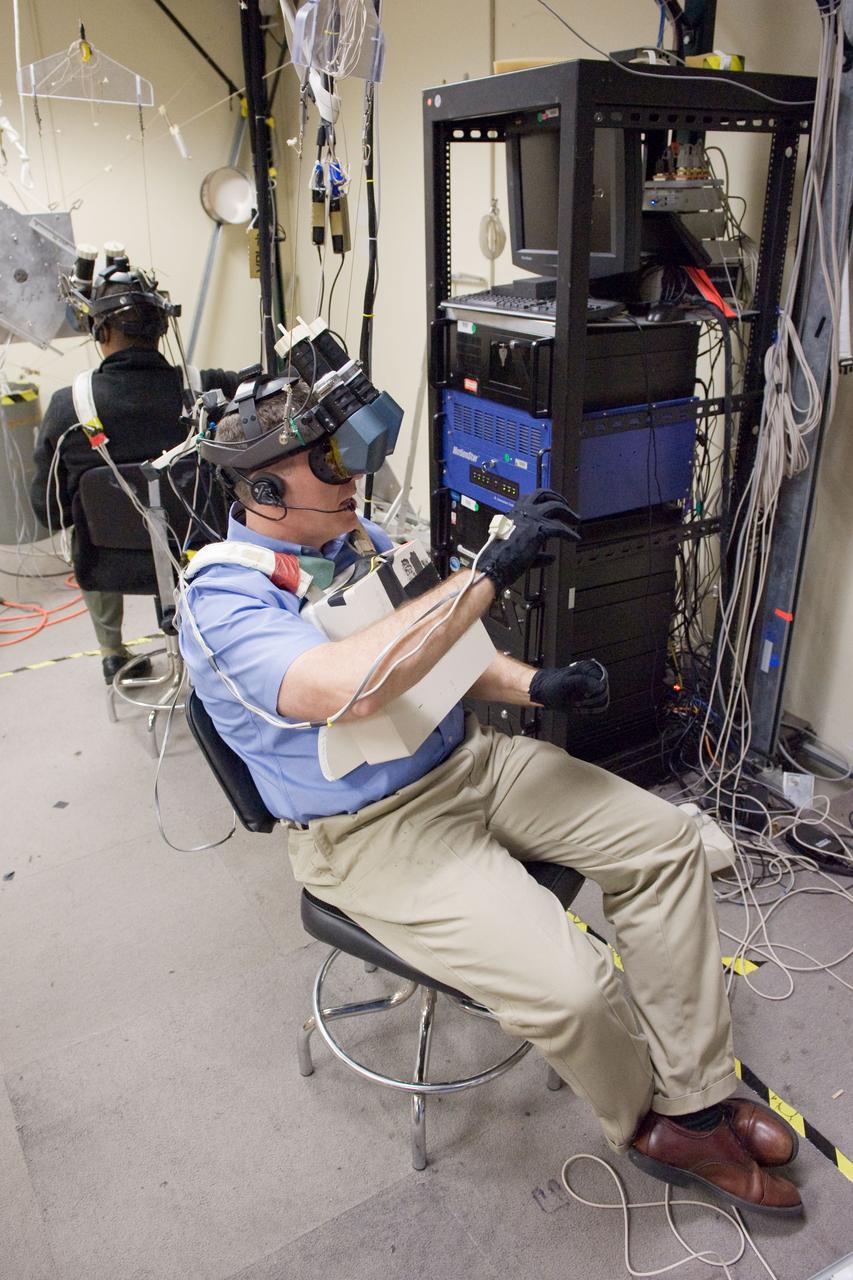 JSC2011-E-006300 (24 Jan. 2011) --- NASA astronauts Steve Bowen (foreground) and Alvin Drew, both STS-133 mission specialists, use virtual reality hardware in the Space Vehicle Mock-up Facility at NASA's Johnson Space Center to rehearse some of their duties on the upcoming mission to the International Space Station. This type of virtual reality training allows the astronauts to wear a helmet and special gloves while looking at computer displays simulating actual movements around the various locations on the station hardware with which they will be working. Photo credit: NASA or National Aeronautics and Space Administration
