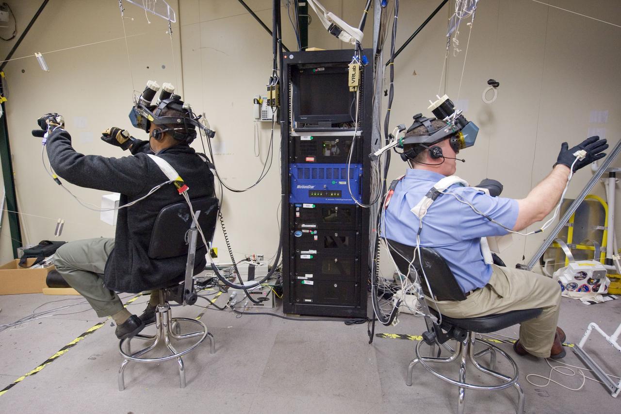 JSC2011-E-006302 (24 Jan. 2011) --- NASA astronauts Alvin Drew (left) and Steve Bowen, both STS-133 mission specialists, use virtual reality hardware in the Space Vehicle Mock-up Facility at NASA's Johnson Space Center to rehearse some of their duties on the upcoming mission to the International Space Station. This type of virtual reality training allows the astronauts to wear a helmet and special gloves while looking at computer displays simulating actual movements around the various locations on the station hardware with which they will be working. Photo credit: NASA or National Aeronautics and Space Administration