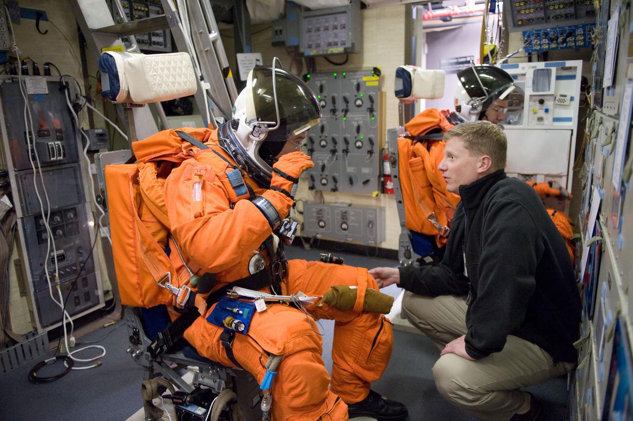 JSC2011-E-006687 (27 Jan. 2011) --- NASA astronauts Steve Bowen (left foreground) and Michael Barratt, both STS-133 mission specialists, attired in training versions of their shuttle launch and entry suits, participate in a training session in the fixed-base shuttle mission simulator (SMS) in the Jake Garn Simulation and Training Facility at NASA's Johnson Space Center. Crew instructor Gary W. Kilgo assisted the crew members. Photo credit: NASA or National Aeronautics and Space Administration