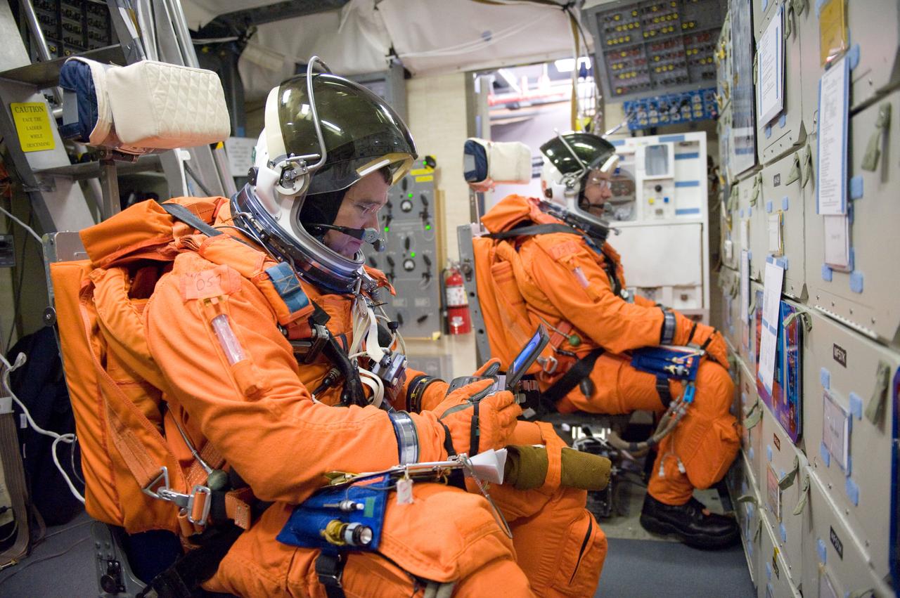 JSC2011-E-006690 (27 Jan. 2011) --- NASA astronauts Steve Bowen (foreground) and Michael Barratt, both STS-133 mission specialists, attired in training versions of their shuttle launch and entry suits, participate in a training session in the fixed-base shuttle mission simulator (SMS) in the Jake Garn Simulation and Training Facility at NASA's Johnson Space Center. Photo credit: NASA or National Aeronautics and Space Administration