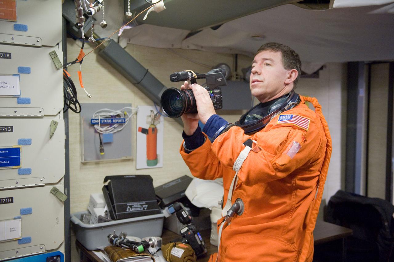 JSC2011-E-006704 (27 Jan. 2011) --- NASA astronaut Michael Barratt, STS-133 mission specialist, attired in a training version of his shuttle launch and entry suit, uses a High Definition Video (HDV) camera during a training session in the fixed-base shuttle mission simulator (SMS) in the Jake Garn Simulation and Training Facility at NASA's Johnson Space Center. Photo credit: NASA or National Aeronautics and Space Administration