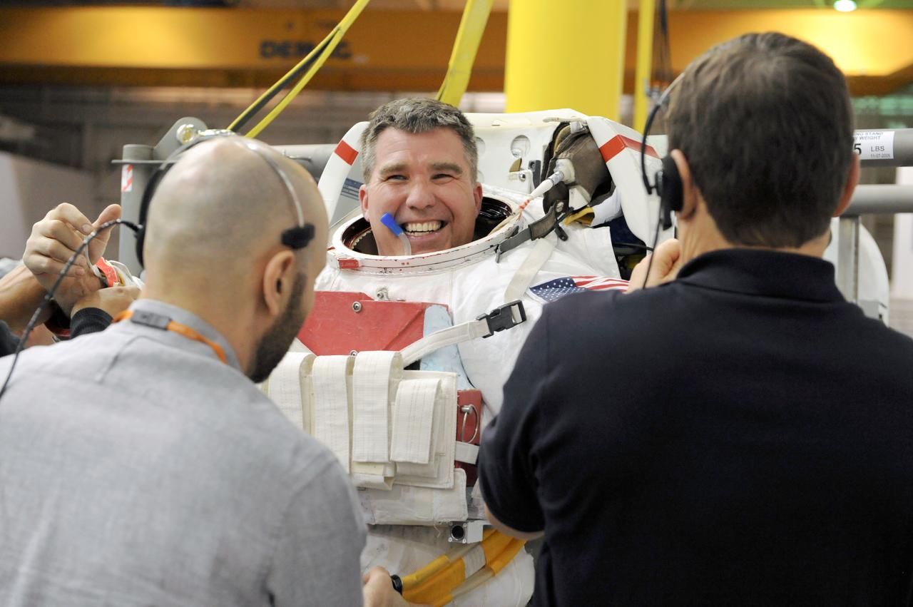 JSC2011-E-013868 (28 Jan. 2011) --- NASA astronaut Steve Bowen, STS-133 mission specialist, gets help donning a training version of his Extravehicular Mobility Unit (EMU) spacesuit in preparation for a spacewalk training session in the waters of the Neutral Buoyancy Laboratory (NBL) near NASA's Johnson Space Center. Photo credit: NASA or National Aeronautics and Space Administration