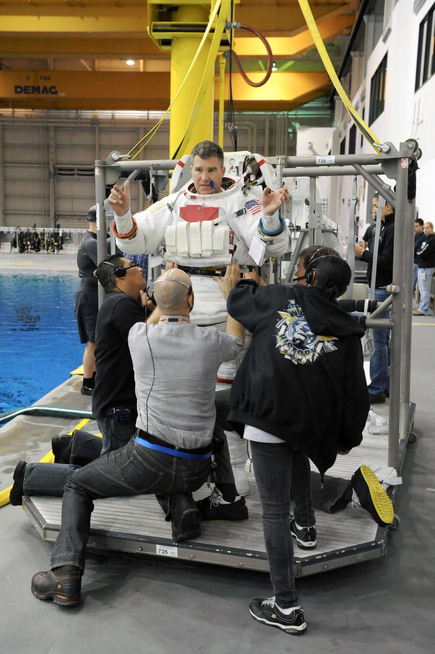 JSC2011-E-013870 (28 Jan. 2011) --- NASA astronaut Steve Bowen, STS-133 mission specialist, gets help donning a training version of his Extravehicular Mobility Unit (EMU) spacesuit in preparation for a spacewalk training session in the waters of the Neutral Buoyancy Laboratory (NBL) near NASA's Johnson Space Center. Photo credit: NASA or National Aeronautics and Space Administration