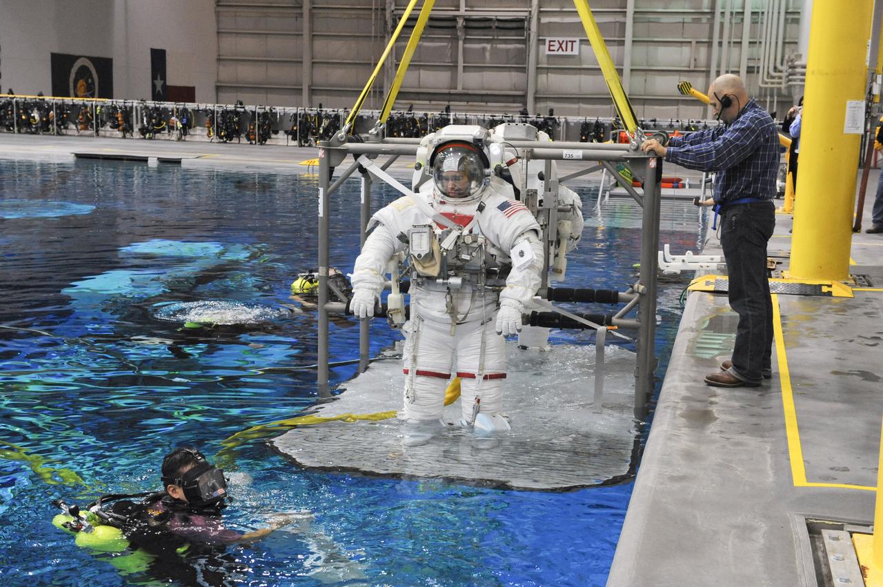 JSC2011-E-013876 (28 Jan. 2011) --- NASA astronauts Steve Bowen and Alvin Drew (mostly obscured), both STS-133 mission specialists, attired in training versions of their Extravehicular Mobility Unit (EMU) spacesuits, are submerged in the waters of the Neutral Buoyancy Laboratory (NBL) near NASA's Johnson Space Center. Divers are in the water to assist Bowen and Drew in their rehearsal, which is intended to help prepare them for work on the exterior of the International Space Station. Photo credit: NASA or National Aeronautics and Space Administration