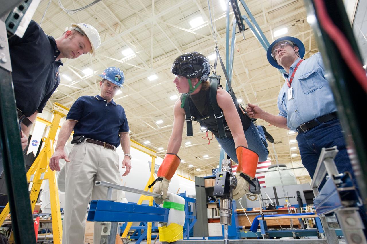 JSC2011-E-017411 (16 Feb. 2011) --- NASA astronaut Sandy Magnus, STS-135 mission specialist, participates in an extravehicular activity (EVA) training session in the Partial Gravity Simulator (POGO) test area in the Space Vehicle Mock-up Facility at NASA's Johnson Space Center. NASA astronaut Rex Walheim (left background), mission specialist, looks on. Photo credit: NASA or National Aeronautics and Space Administration