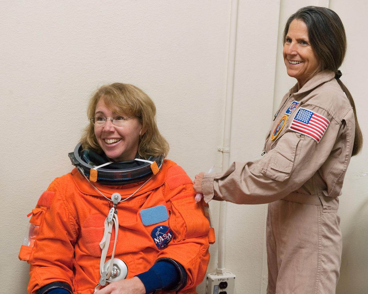 JSC2011-E-023112 (2 March 2011) --- NASA astronaut Sandy Magnus, STS-135 mission specialist, dons a training version of her shuttle launch and entry suit in preparation for a training session in the fixed-base shuttle mission simulator (SMS) in the Jake Garn Simulation and Training Facility at NASA's Johnson Space Center. Suit technician Toni Cost-Davis assisted Magnus. Photo credit: NASA or National Aeronautics and Space Administration